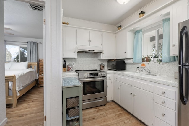 kitchen featuring sink, appliances with stainless steel finishes, white cabinetry, tasteful backsplash, and light wood-type flooring