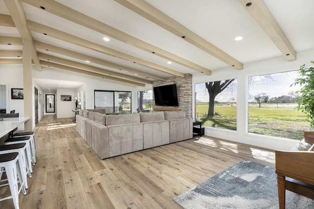 living room with vaulted ceiling with beams and light wood-type flooring