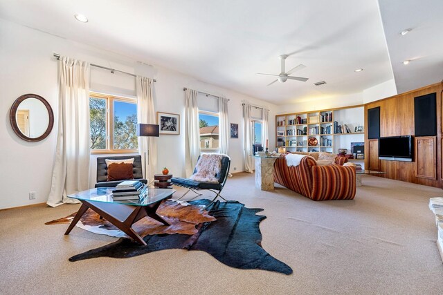 living room with ceiling fan, carpet, and built in shelves