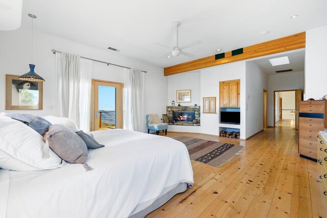 bedroom featuring a stone fireplace, ceiling fan, and light wood-type flooring