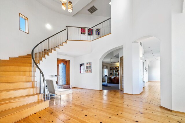 foyer entrance featuring a towering ceiling and light wood-type flooring