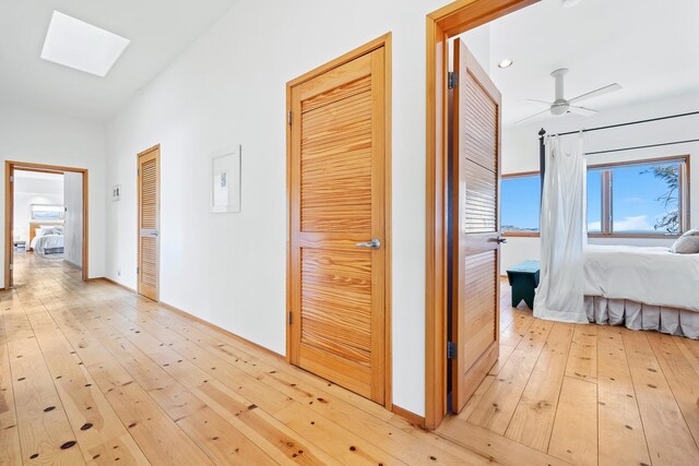 corridor with a skylight and light hardwood / wood-style floors