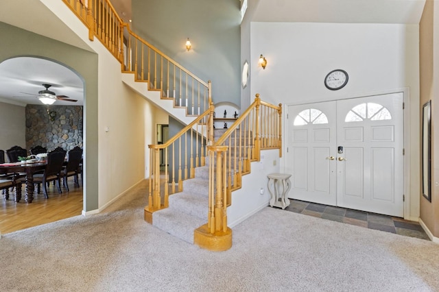 carpeted foyer entrance with ceiling fan and a towering ceiling