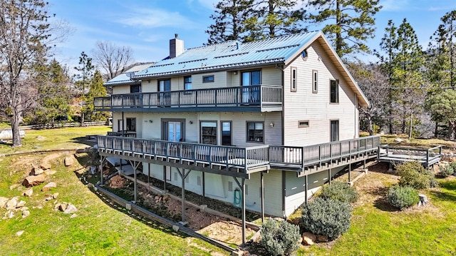 rear view of house with a yard, a balcony, and a wooden deck