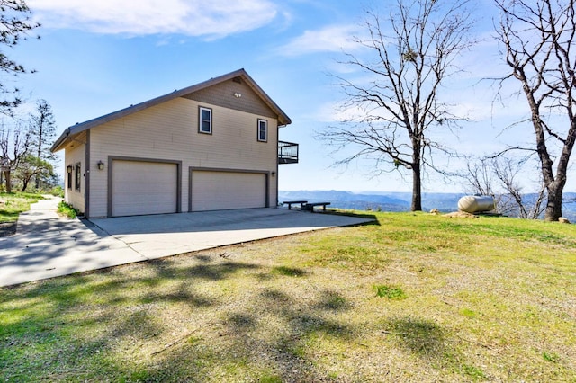 view of side of property featuring a lawn, a mountain view, and a garage