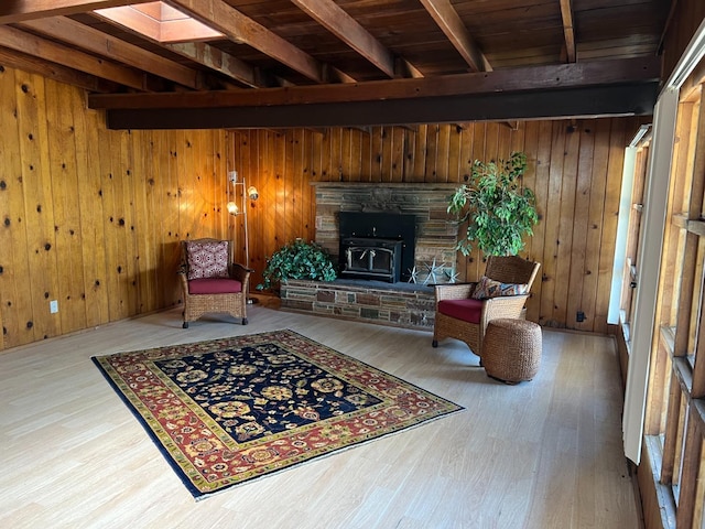 living area with wood-type flooring, wooden walls, and a wood stove