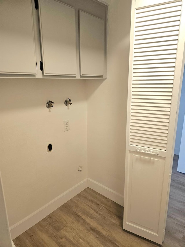 laundry area with hardwood / wood-style flooring, electric dryer hookup, and cabinets