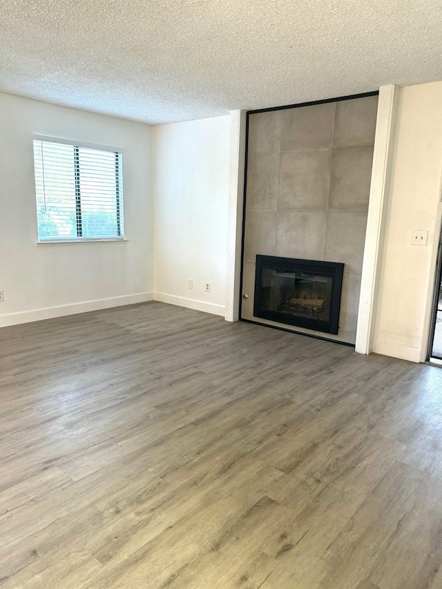 unfurnished living room with a large fireplace, wood-type flooring, and a textured ceiling