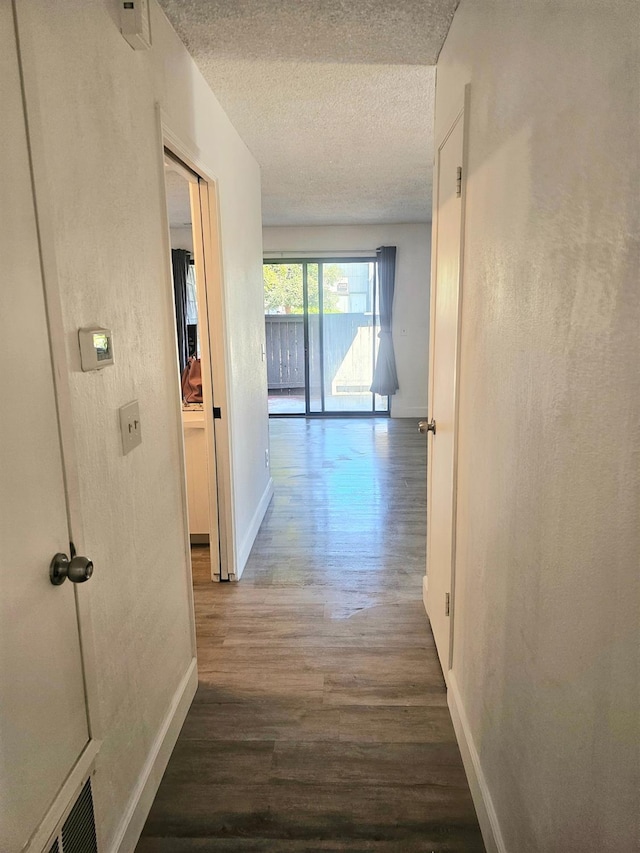 corridor featuring a textured ceiling and dark wood-type flooring