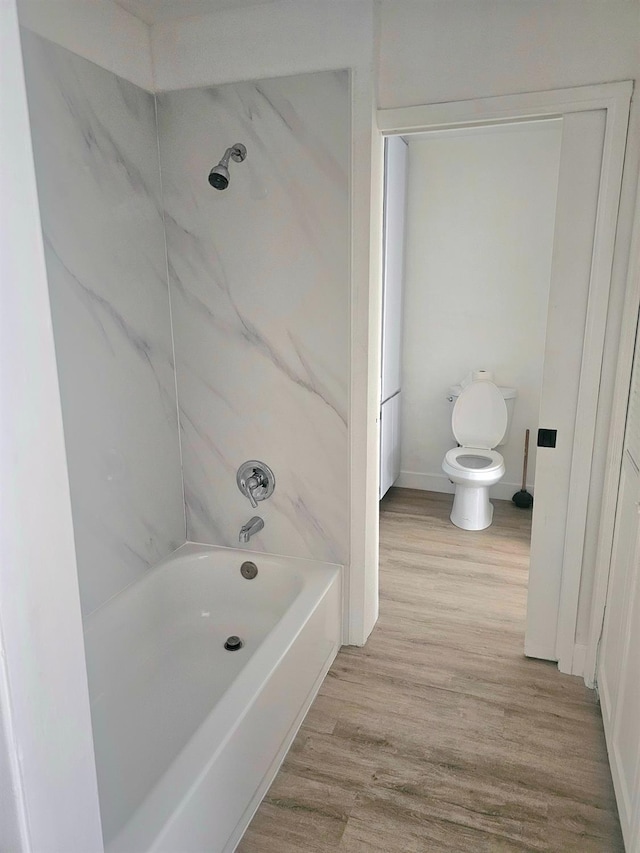 bathroom featuring hardwood / wood-style flooring, toilet, and shower / washtub combination