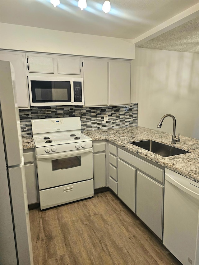 kitchen with dark hardwood / wood-style floors, white appliances, sink, and tasteful backsplash