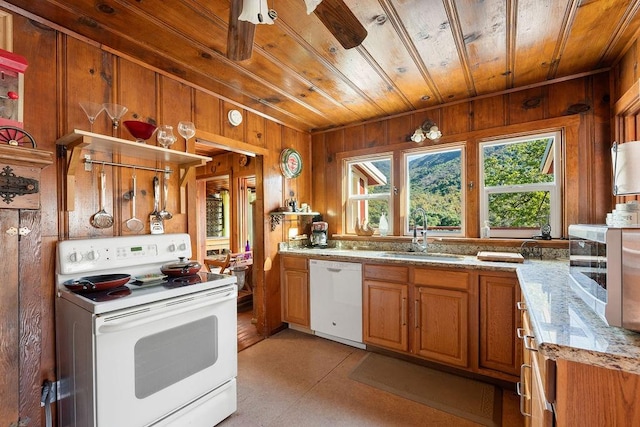 kitchen with sink, white appliances, wooden ceiling, wood walls, and light stone countertops