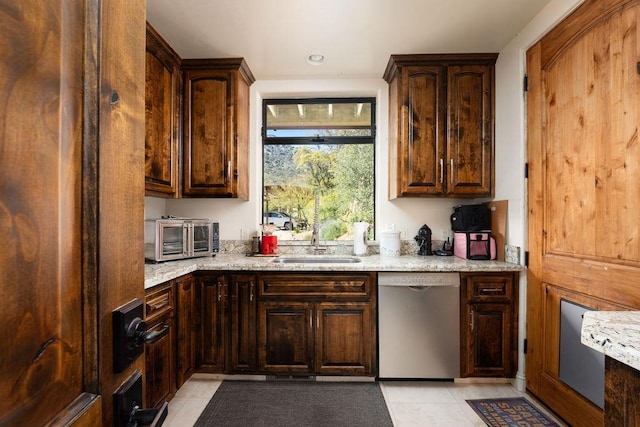 kitchen featuring dark brown cabinetry, sink, dishwasher, light tile flooring, and light stone countertops