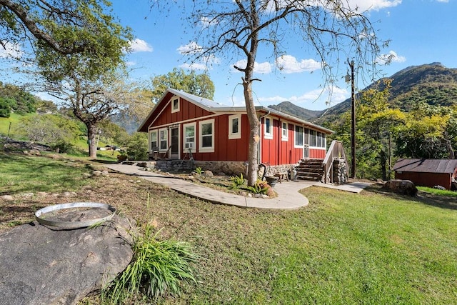 rear view of house featuring a mountain view and a lawn