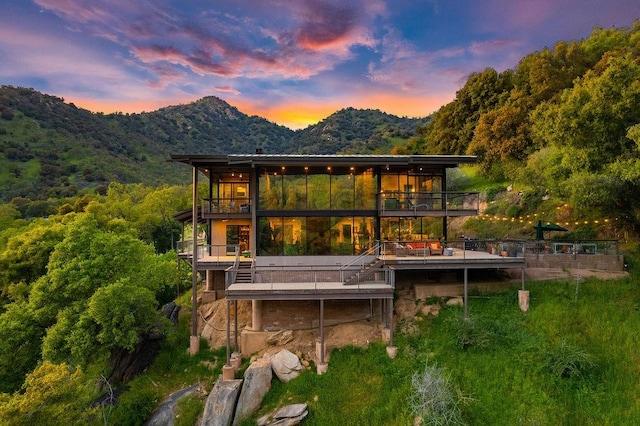 back house at dusk featuring a mountain view and a balcony