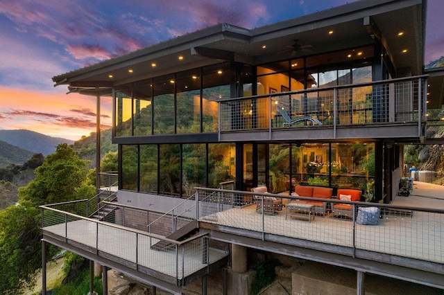 back house at dusk featuring an outdoor living space and a balcony