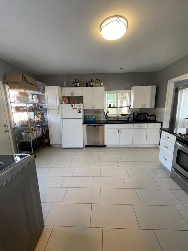 kitchen featuring decorative backsplash, stainless steel appliances, white cabinetry, and sink