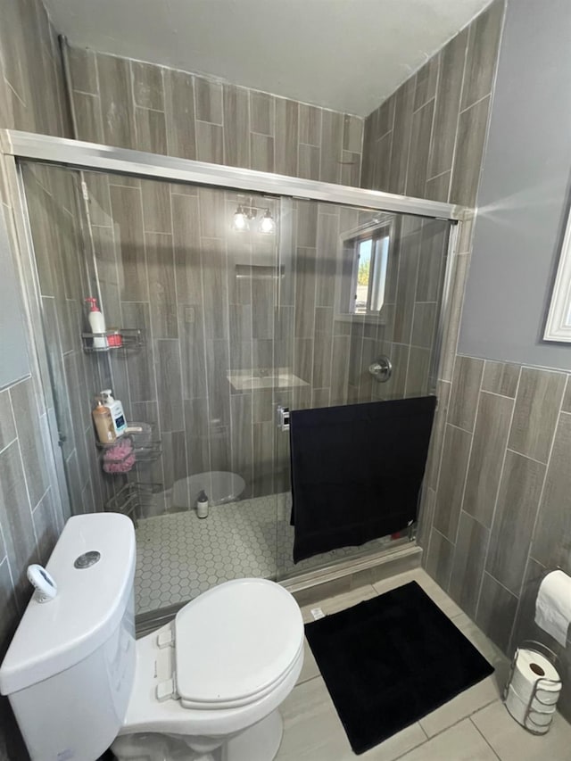 bathroom featuring an enclosed shower, tile patterned flooring, toilet, and tile walls