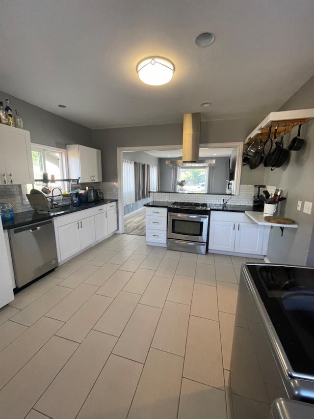 kitchen featuring white cabinets, backsplash, stainless steel appliances, and island exhaust hood