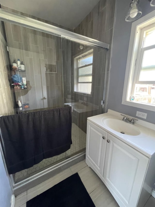 bathroom featuring a wealth of natural light, tile patterned flooring, vanity, and an enclosed shower