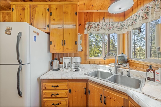 kitchen featuring white refrigerator, wooden ceiling, and sink