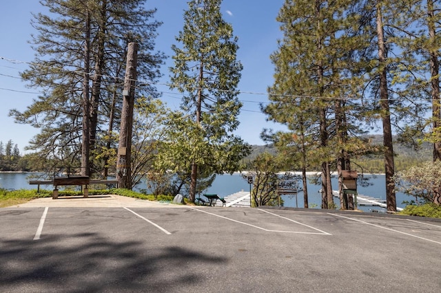 view of vehicle parking featuring a boat dock and a water view