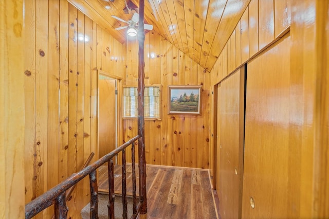 corridor with lofted ceiling, hardwood / wood-style flooring, wooden walls, and wood ceiling