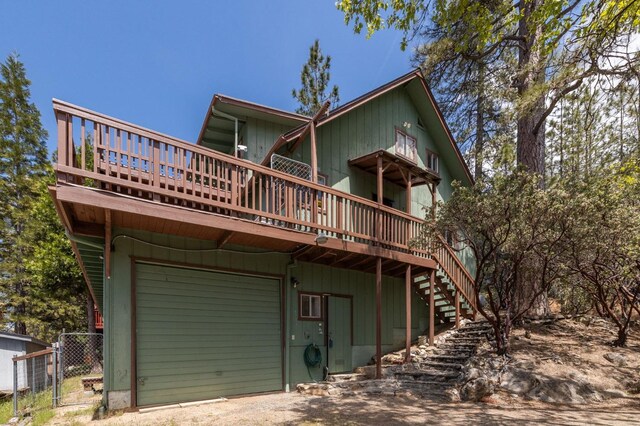 rear view of house featuring a garage and a wooden deck