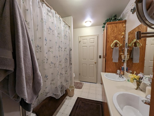 bathroom with tile patterned floors, curtained shower, double vanity, and a sink