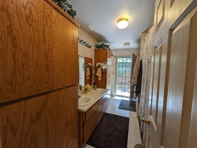 full bathroom with double vanity, visible vents, tile patterned floors, and a sink