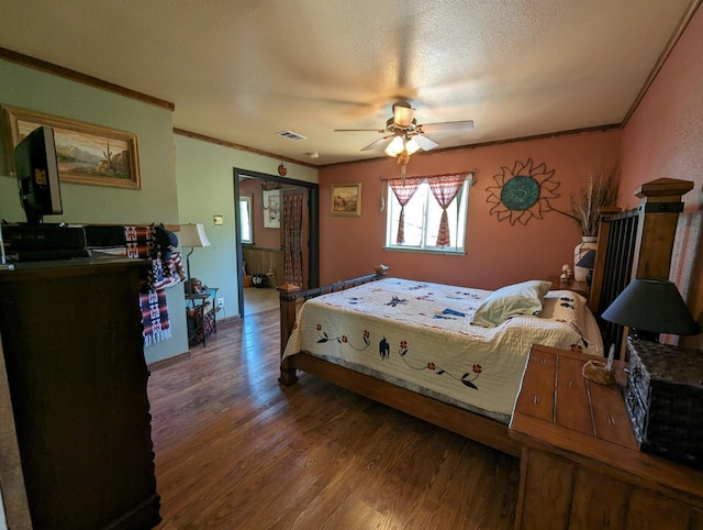 bedroom with visible vents, crown molding, wood finished floors, a textured ceiling, and a ceiling fan