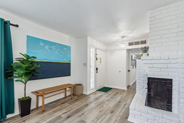 925 S Purdue Ave, Fresno, CA 93727 - foyer entrance featuring baseboards, light wood finished floors, a brick fireplace, and a chandelier