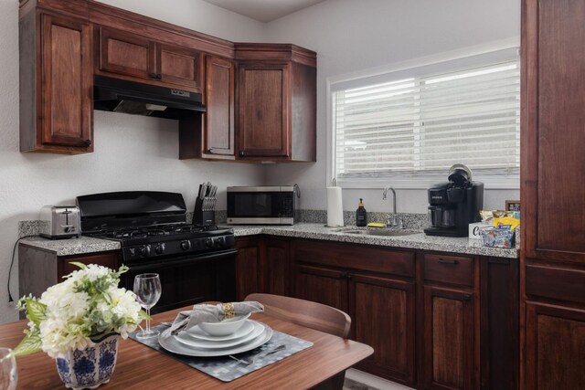 925 S Purdue Ave, Fresno, CA 93727 - kitchen with gas stove, under cabinet range hood, stainless steel microwave, a sink, and light stone counters