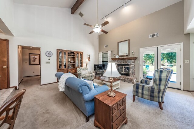 living room featuring a fireplace, beam ceiling, ceiling fan, track lighting, and light colored carpet