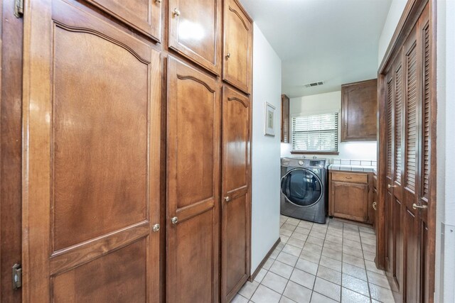 laundry area featuring cabinets, washer / dryer, and light tile patterned flooring