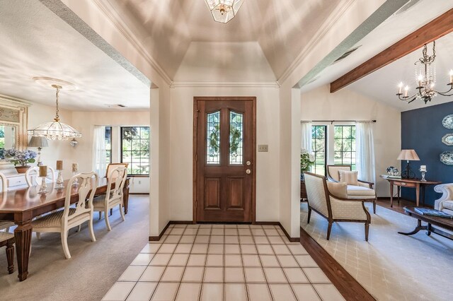 carpeted foyer featuring vaulted ceiling with beams, ornamental molding, and a chandelier