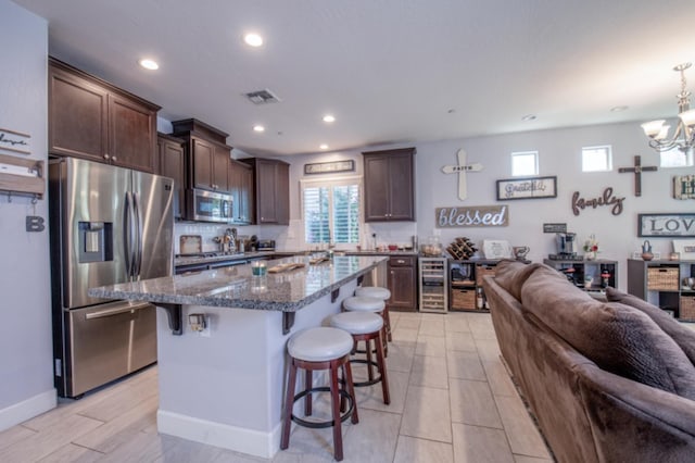 kitchen with dark stone countertops, a kitchen island, appliances with stainless steel finishes, a breakfast bar area, and light tile floors