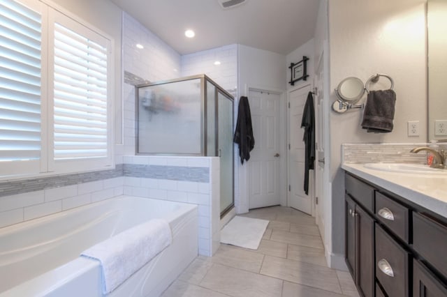 bathroom with tile floors, shower with separate bathtub, and vanity with extensive cabinet space