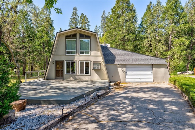 view of front facade featuring a garage, an outdoor structure, and a wooden deck