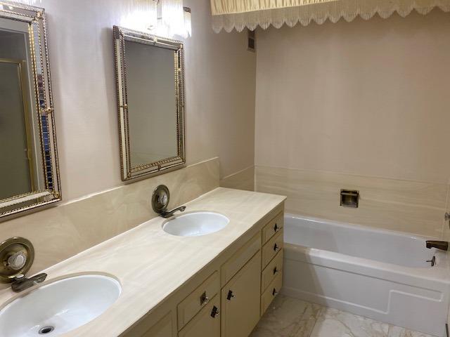 bathroom featuring tile floors, dual vanity, and a bathing tub