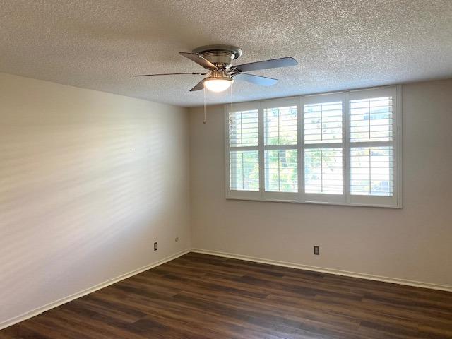 spare room with a textured ceiling, ceiling fan, and dark hardwood / wood-style flooring