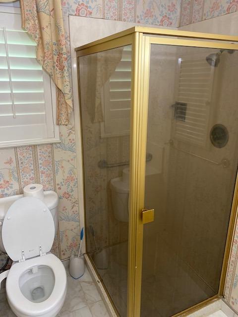 bathroom with tile flooring, walk in shower, and toilet