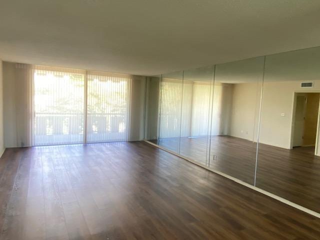 interior space with a wall of windows, access to outside, and dark wood-type flooring