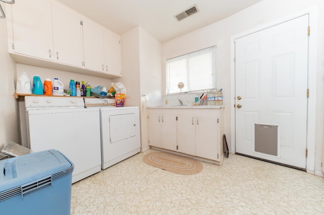 clothes washing area with cabinets, light tile floors, and washing machine and clothes dryer