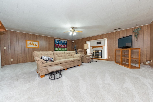 carpeted living room featuring wood walls and ceiling fan