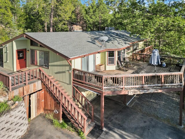 rear view of property with roof with shingles and a deck