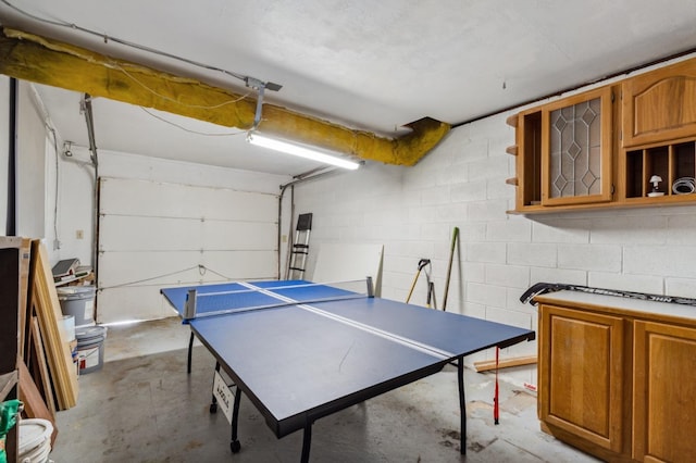 playroom featuring concrete block wall, concrete floors, and a garage