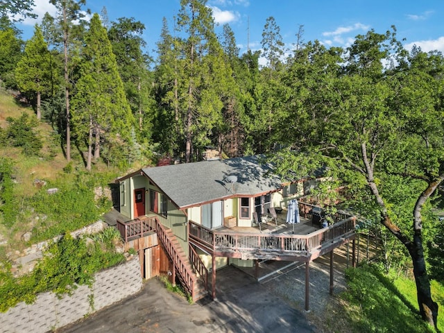 view of front of house with stairway, a wooden deck, and a shingled roof