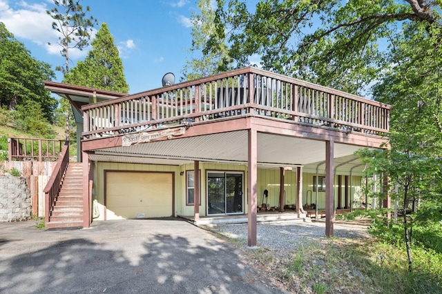 view of front of property featuring a garage, a deck, aphalt driveway, board and batten siding, and stairway
