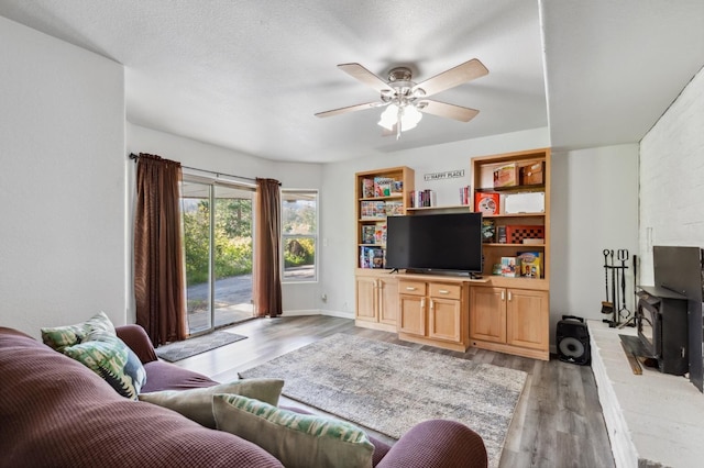 living room with ceiling fan, a wood stove, and light wood-style floors